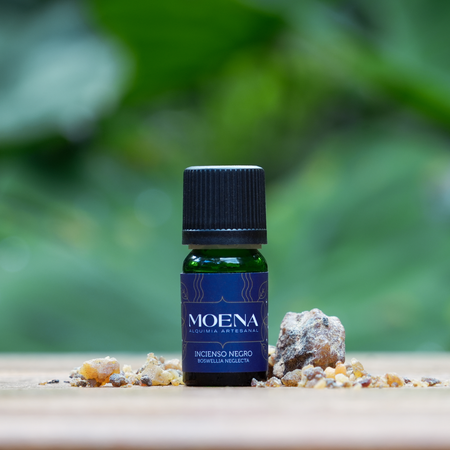 Bottle of Moena Black Frankincense Essential Oil - Incienso Negro on a wooden surface with a natural background