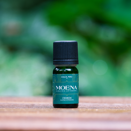 Small green bottle of Lemon Verbena Essential Oil - Cedrón  on a wooden surface with a blurred green background