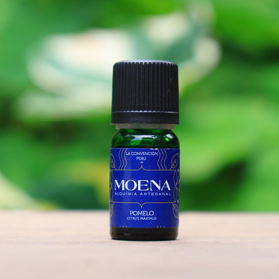 Small bottle of Grapefruit Essential Oil - Pomelo essential oil on a wooden surface with a blurred green background