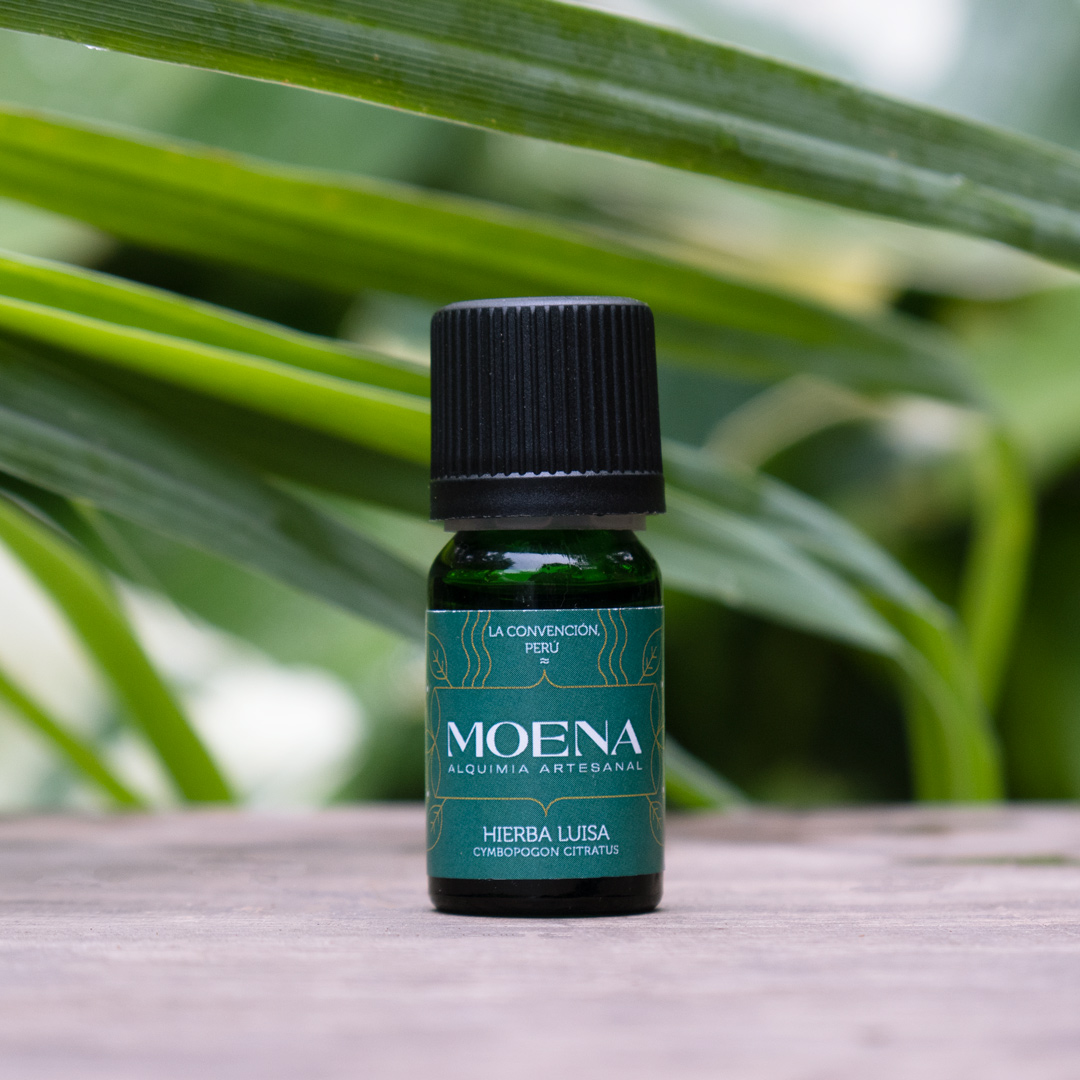 Small green bottle of Lemongrass Essential Oil - Hierba Luisa on a wooden surface with green leaves in the background