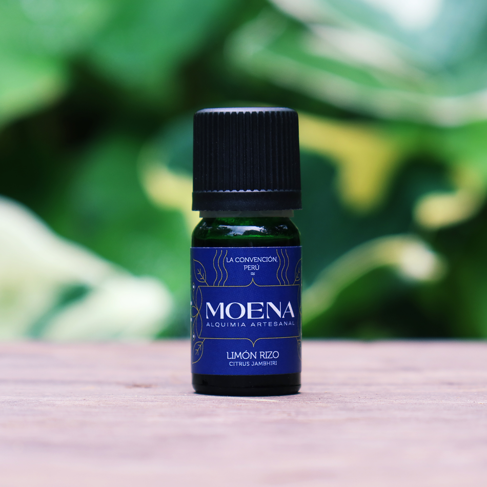 Bottle of Rough Lemon Petitgrain Essential Oil - Limón Rizo on a wooden surface with a blurred green background