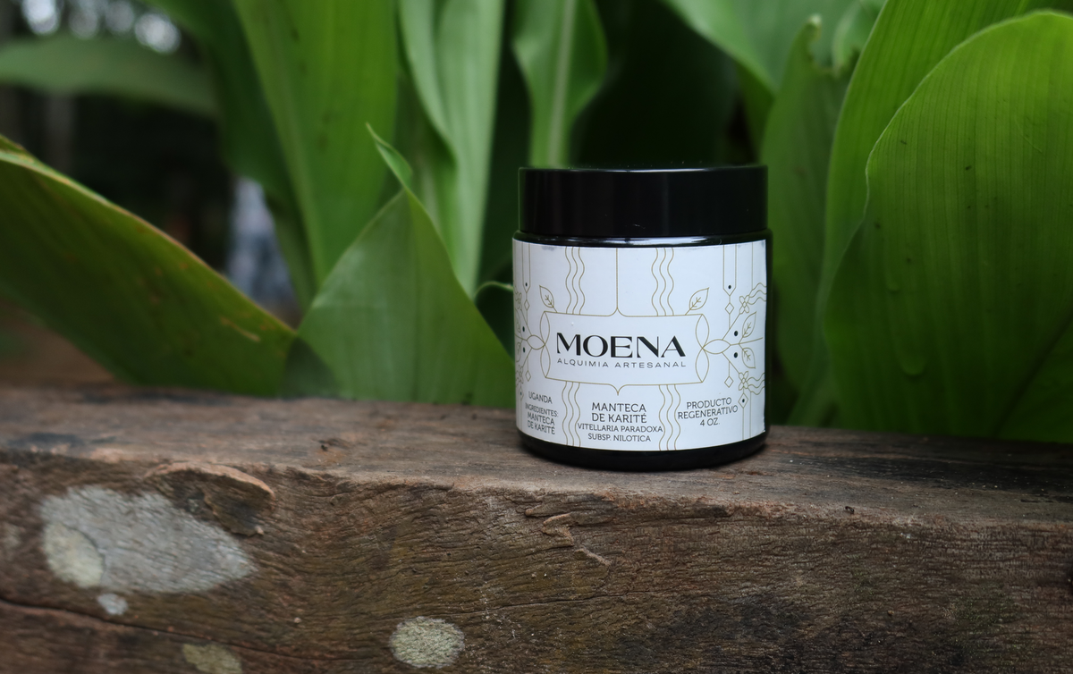 Moena Shea Butter product on a wooden surface with green leaves in the background