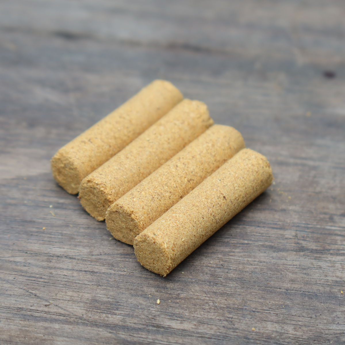 Four cylindrical light brown incense portions on a wooden surface