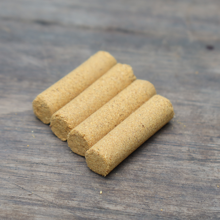 Four cylindrical light brown incense portions on a wooden surface