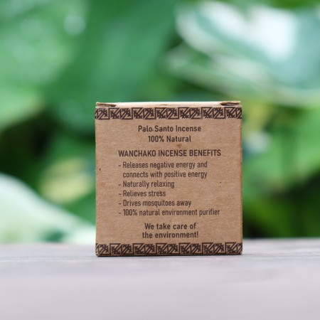 Back of a box of Palo Santo incense with text on a wooden surface and green foliage background